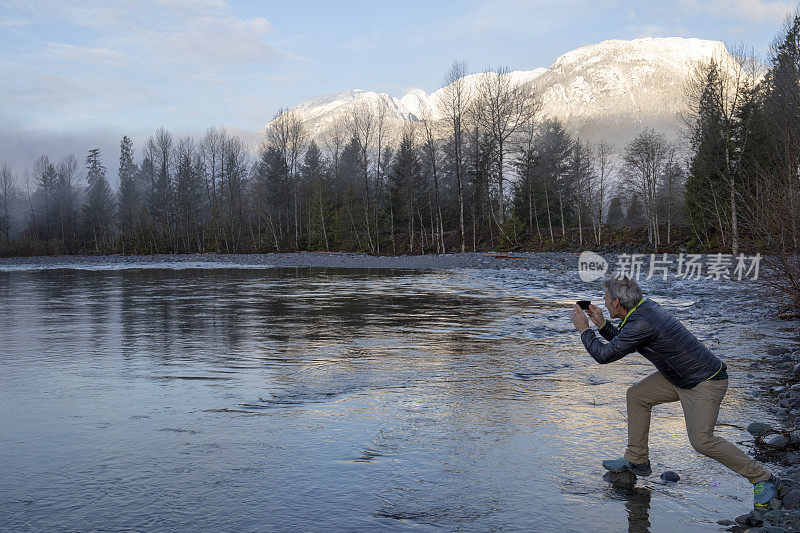 日出时分，一名男子用手机拍摄湖面