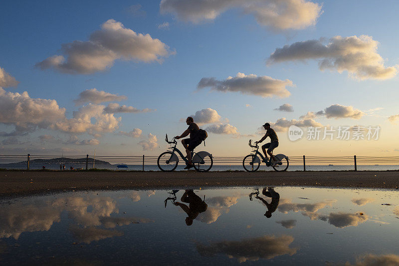 一个骑自行车的人的剪影在日落与模糊的倒影在水与涟漪