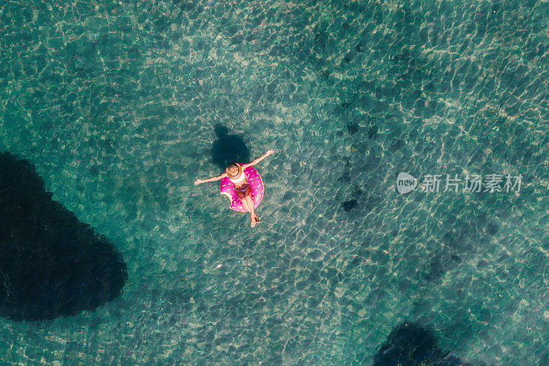 鸟瞰图上的女人漂浮在湖上充气床垫日光浴