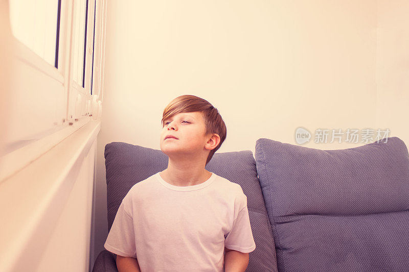一个小男孩坐在窗边向外看