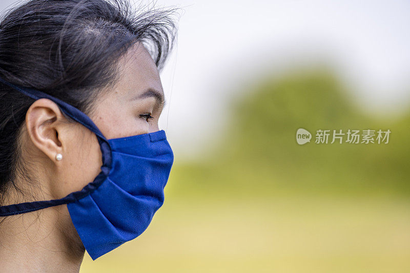 美丽的亚洲女人戴着可重复使用的防护面罩
