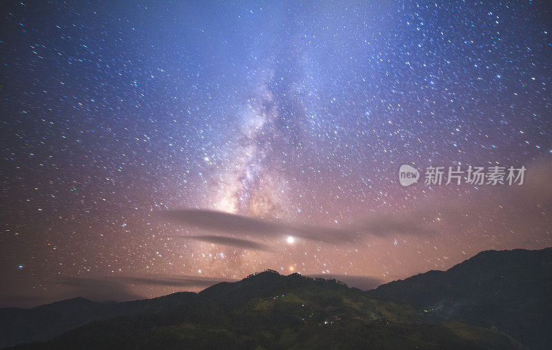 银河系和星星上方的Fansipan山脉与绿色水稻梯田图案在越南朱瓦前景