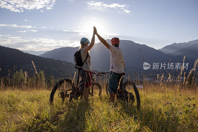 山地电动自行车夫妇在高山草甸击掌