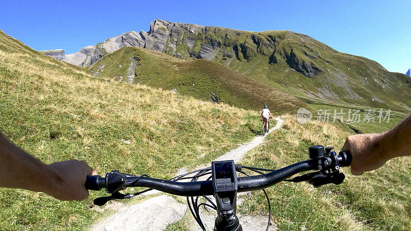 POV透视沿山坡电动自行车后面的一个年轻女子山地自行车