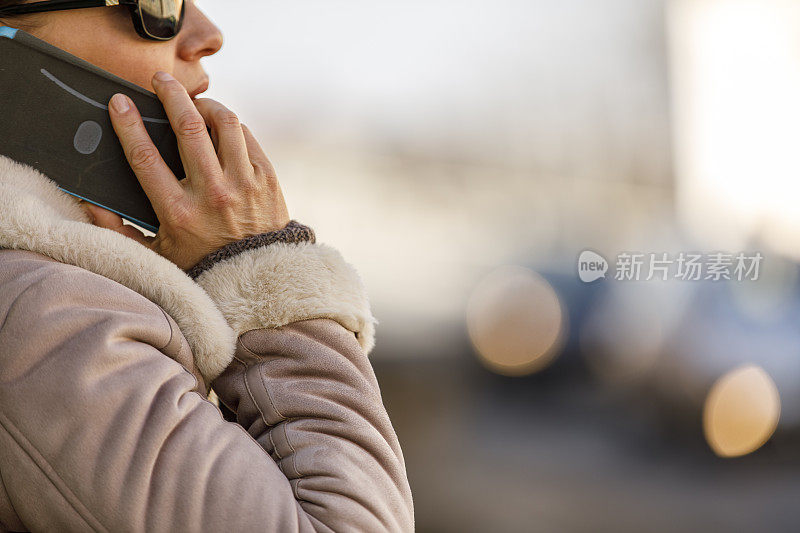 一个女人站在大街上，正在打电话