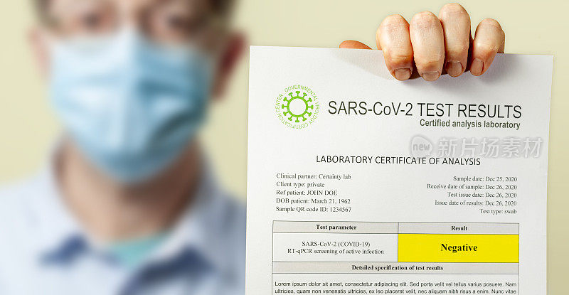 一名戴着外科防护口罩的男子手持一份SARS-CoV-2冠状病毒导致COVID-19的阴性检测文件