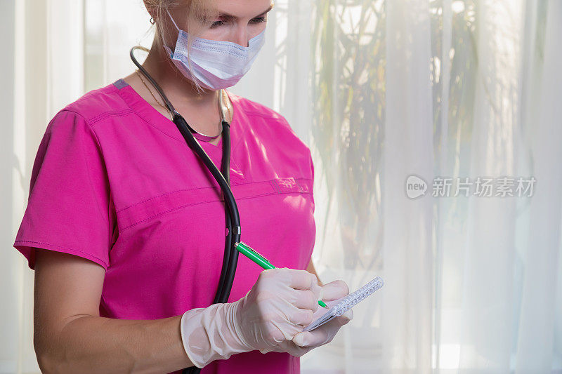 一位戴着口罩和手套的女医生在笔记本上记下病人的体温和血压读数。