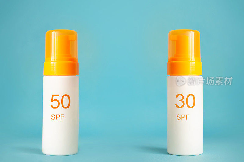 防晒系数为30和50的防晒霜瓶子，背景为水蓝色。防晒，夏季皮肤保湿选择