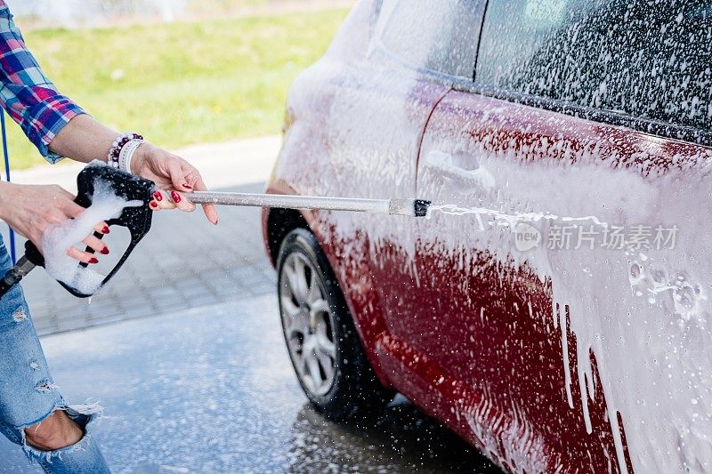 被泡沫覆盖的现代汽车。在洗车室外用加压水手动洗车。