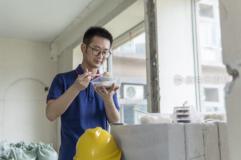 亚洲男工程师在装修工地吃外卖