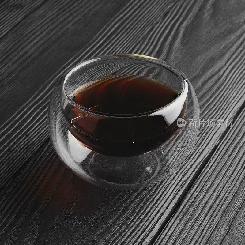 玻璃杯中的普洱茶，深色木制背景