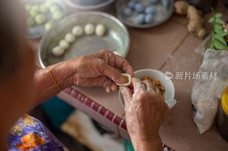 中国老太太准备中国食物“汤圆”糯米球混合花生为冬至节日