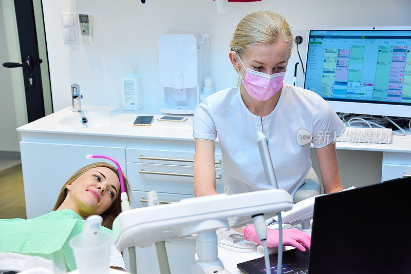 牙科医生和病人看着笔记本电脑屏幕上的牙科扫描。