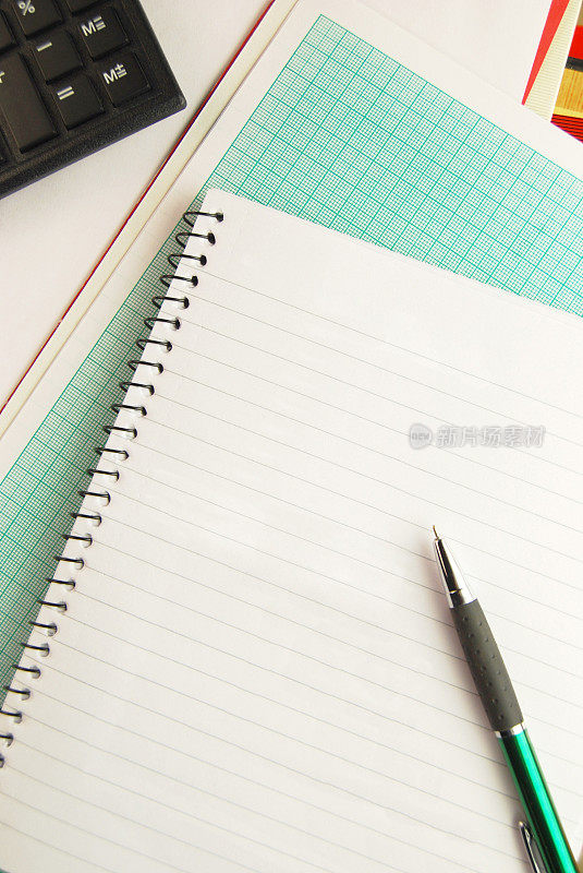 在螺旋形记事本和画图纸的条纹或单行页上画一支绿色的笔，后面还有计算器。