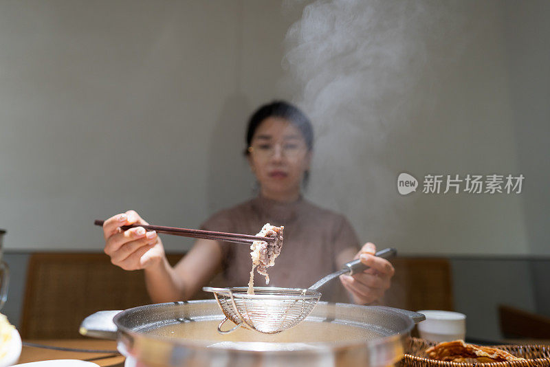 亚洲妇女用筷子夹牛肉