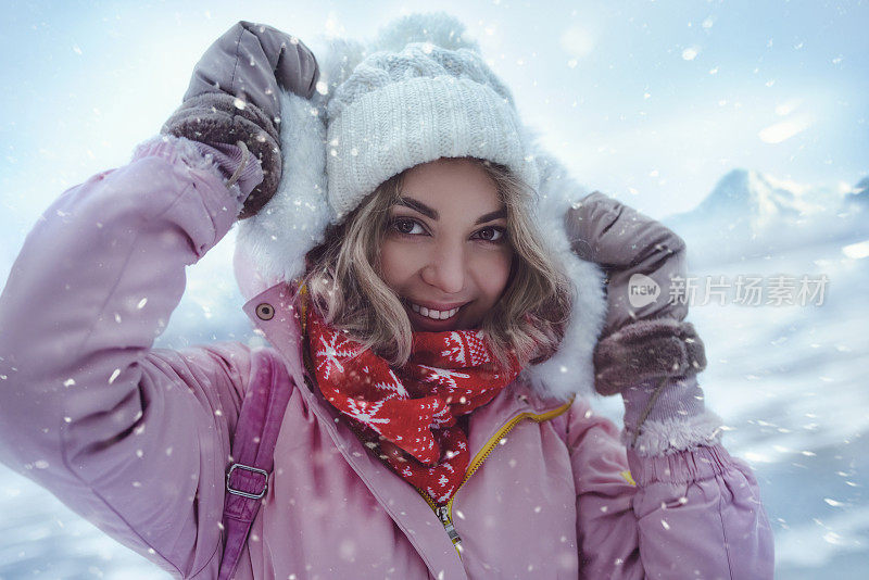滑雪胜地微笑女子的肖像站在结冰的湖岸边，雪花落在她的脸上，冷风吹过，她微笑着。