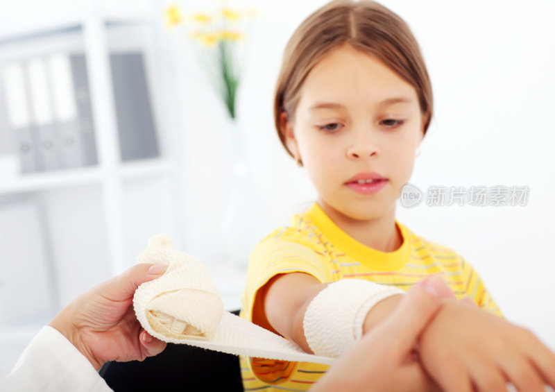 小女孩在医院里用绷带包扎手臂。