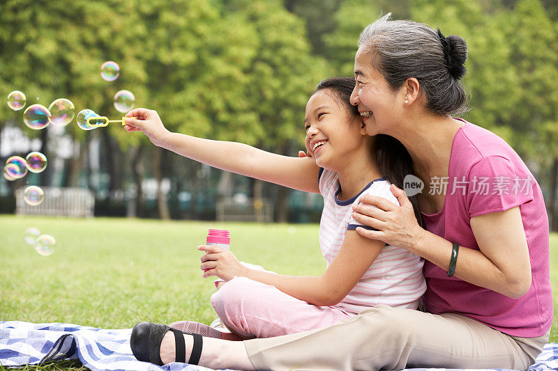 中国奶奶和孙女在公园吹泡泡