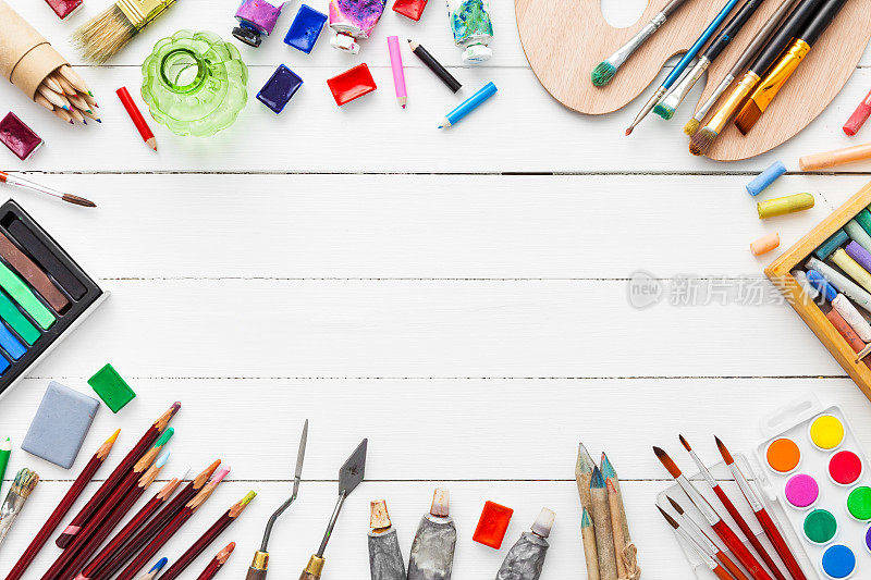 水彩和油画颜料，刷子，铅笔，蜡笔在桌子上。