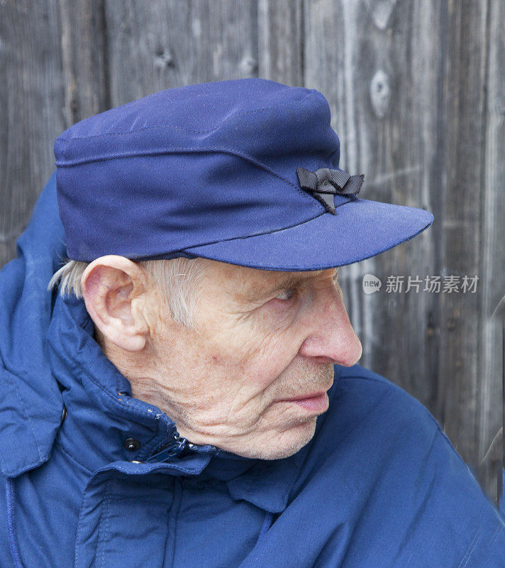 戴蓝帽穿蓝夹克的老人望着远方。