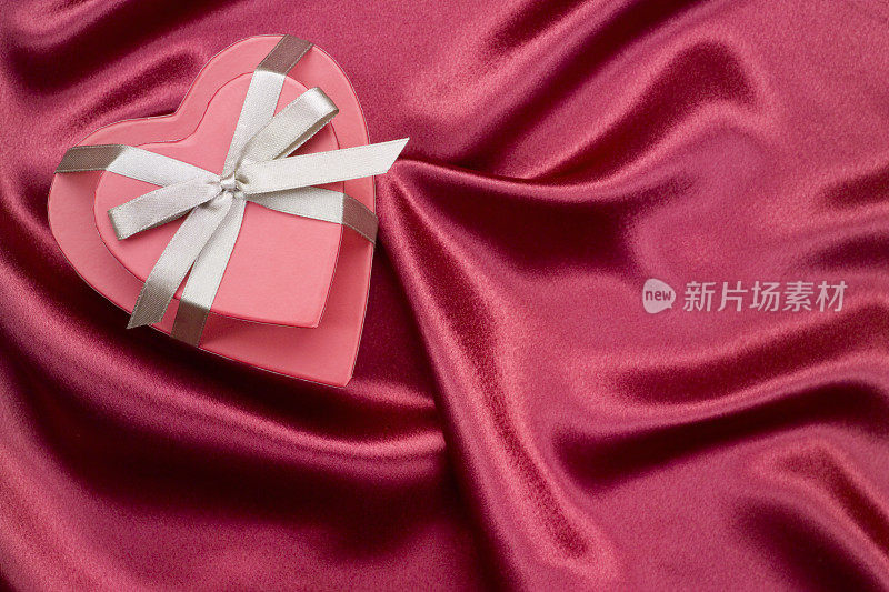 心形盒子与蝴蝶结在红色缎子的背景