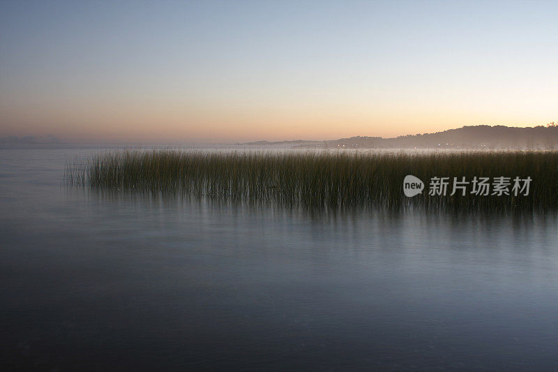 雾蒙蒙的泻湖上的日出。
