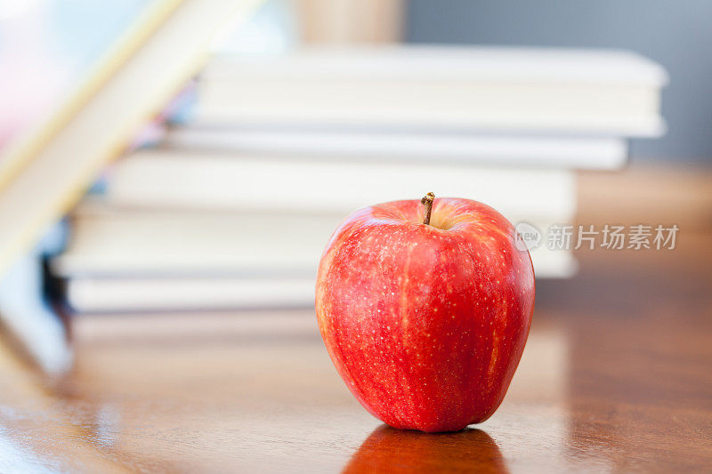 红苹果放在书桌前面的一堆书里