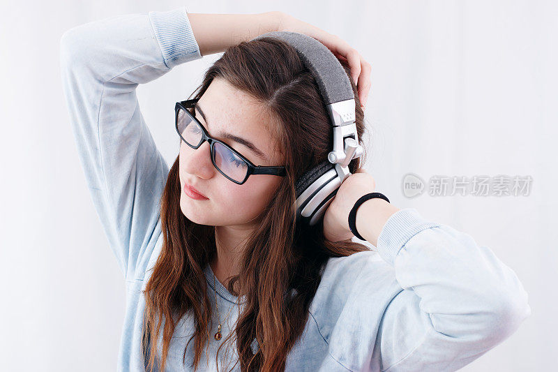 十几岁的女孩戴着耳机听音乐