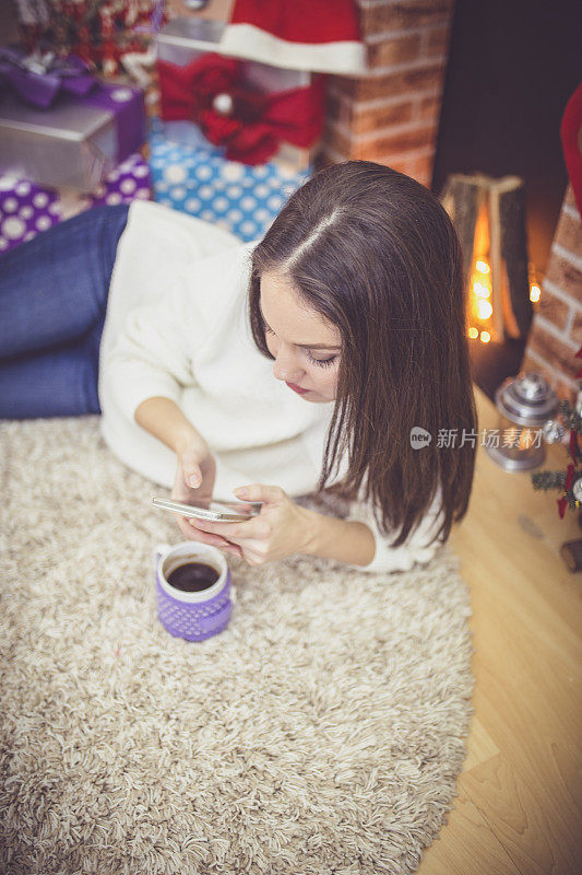 壁炉边拿着马克杯的女人。