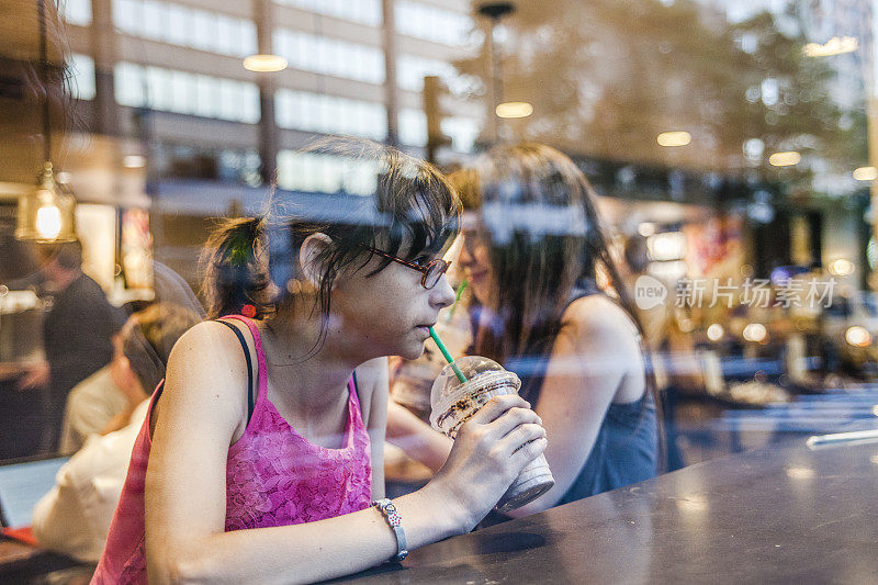 两个十几岁的女孩，姐妹，在一家咖啡馆喝冰咖啡
