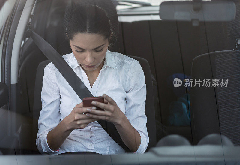 一个女人在车里用手机发短信