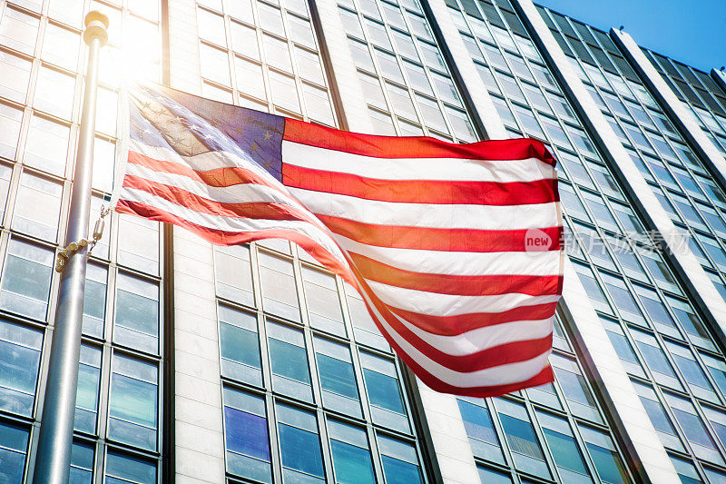 在办公楼前飘扬着美国国旗，太阳耀斑