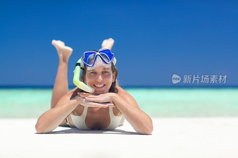 带着潜水镜在海滩上微笑的女人