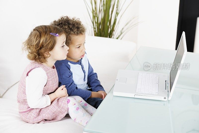 小女孩和小男孩在客厅里使用笔记本电脑