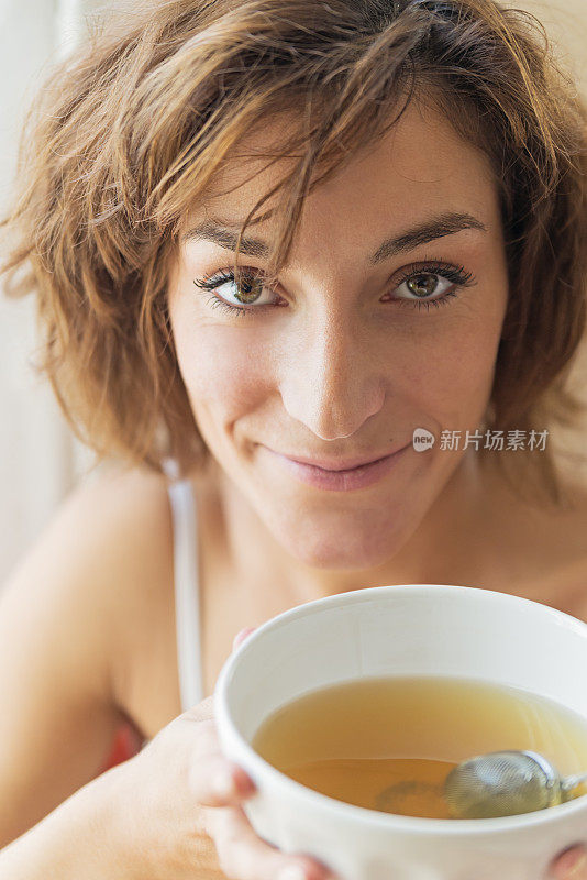 年轻女子早上用碗喝茶。