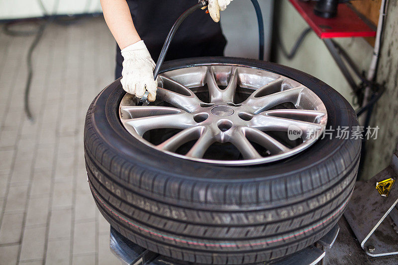 机械师修理汽车轮胎，在车库给轮胎充气