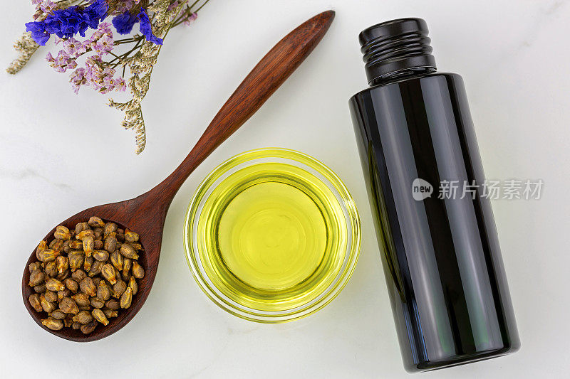 一瓶有机冷榨葡萄籽油和干净的碗与干燥的葡萄籽在木勺
