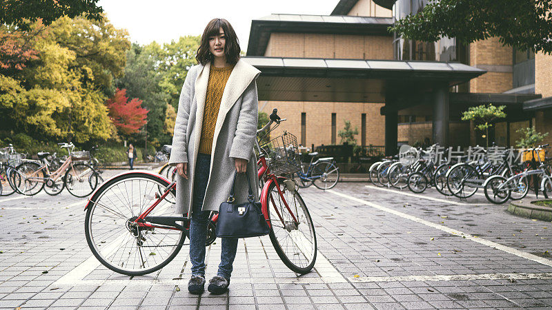 大学里站在自行车旁的年轻女子