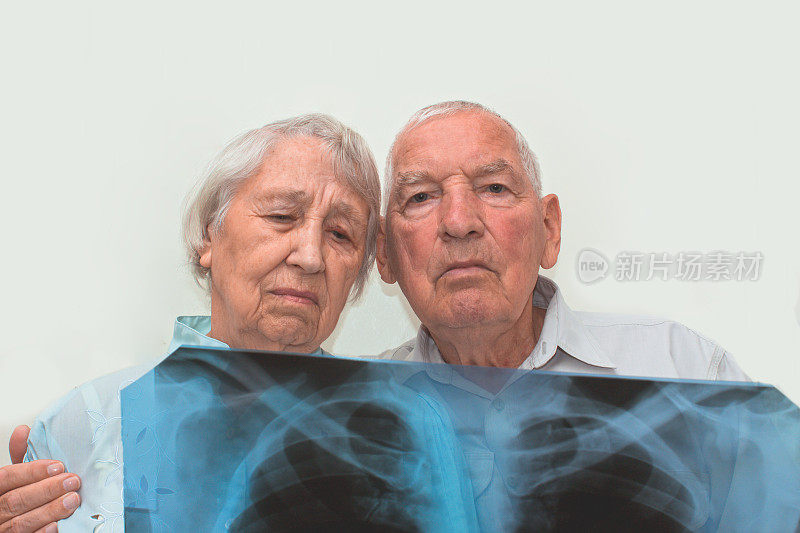 医学，年龄，医疗保健和人们的概念——悲伤的老年妇女和男人在灰色的背景下看心电图