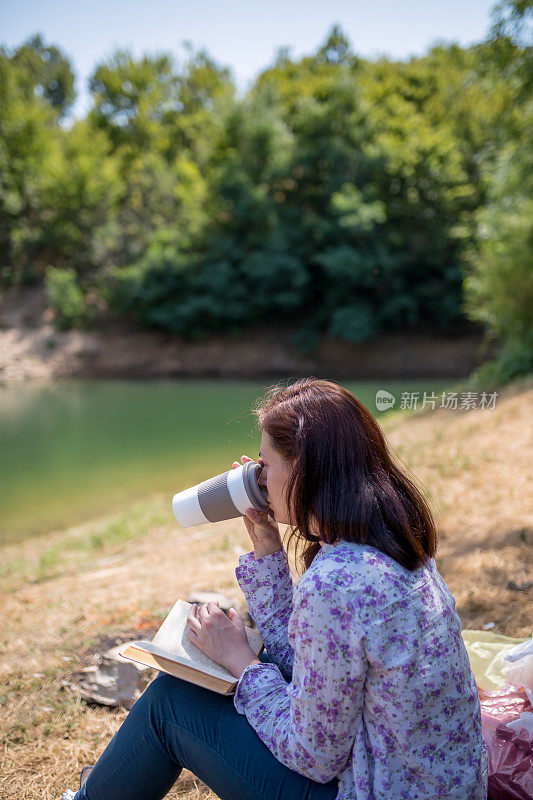 一个年轻女子坐在夕阳下的湖上看书。