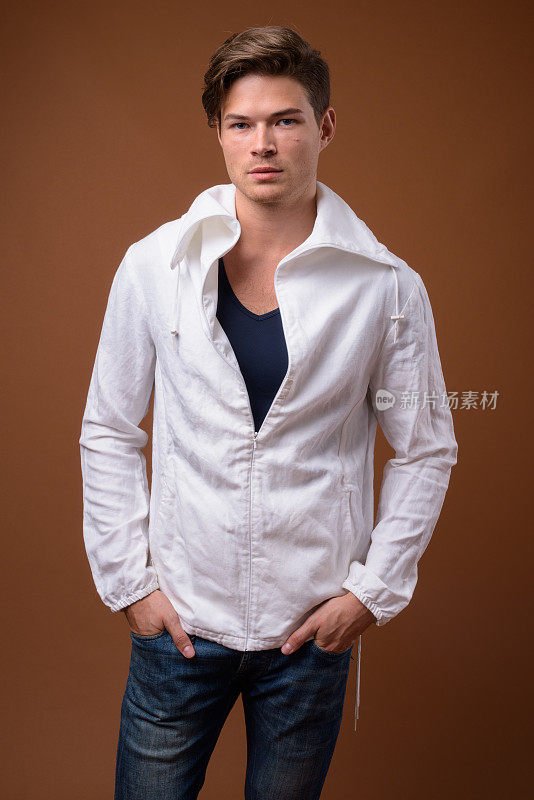 工作室拍摄的年轻英俊的男子穿着高领白色夹克，以彩色背景