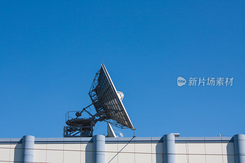 建筑物顶部碟形卫星天线，蓝天背景