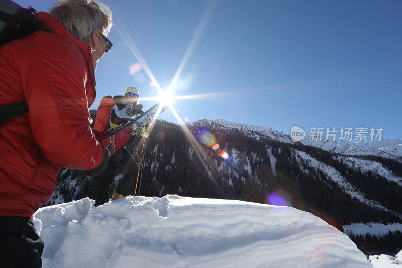 一对夫妇留下滑雪板，在厚厚的积雪中爬上山顶。