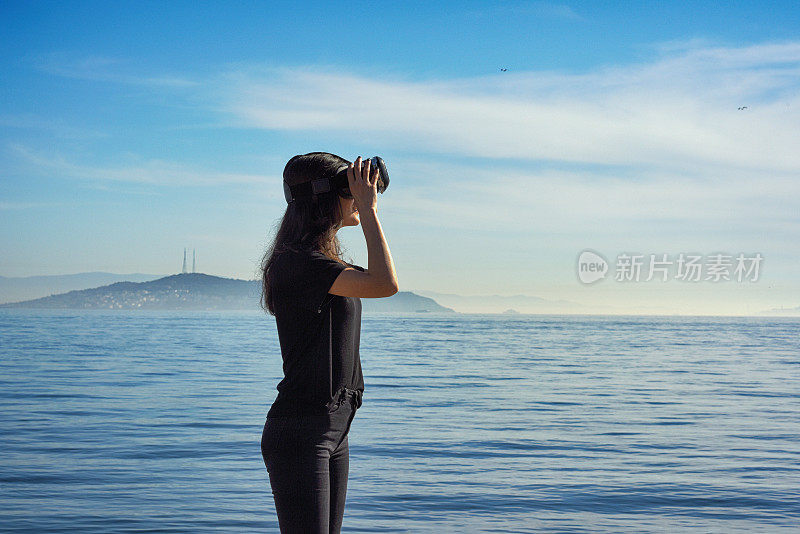 年轻女子在海边通过虚拟现实环顾四周