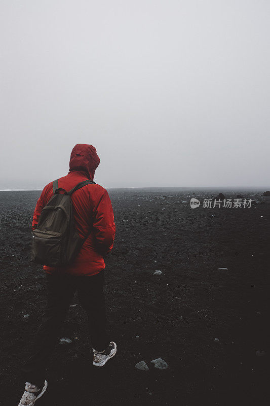 冰岛黑沙滩上的红衣男子