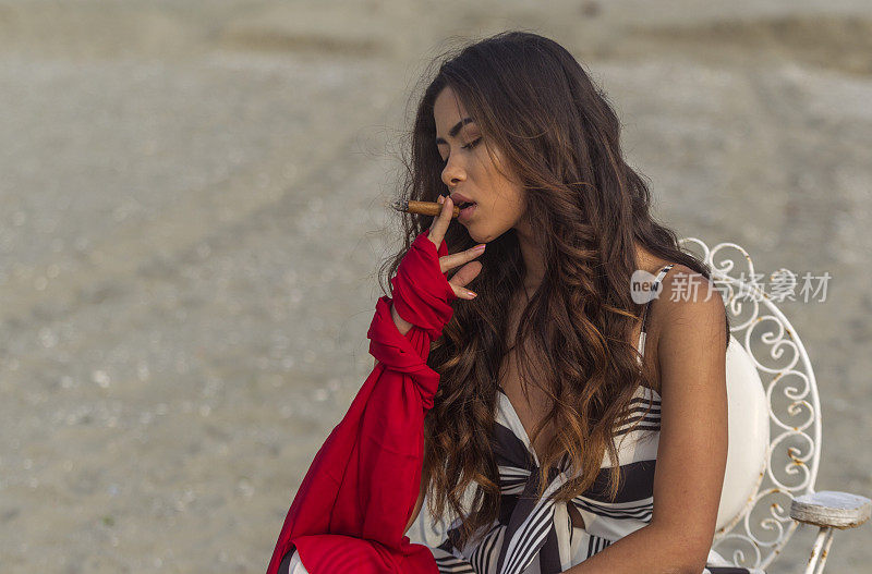 一名年轻的巴西妇女在土耳其伊斯坦布尔的西里夫里海滩上抽着雪茄