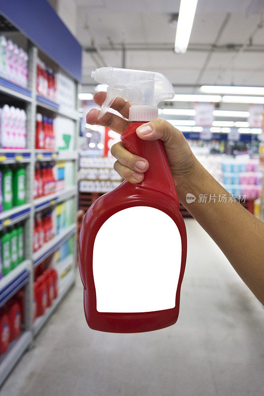 一只手拿着红色的装有洗涤剂的喷瓶