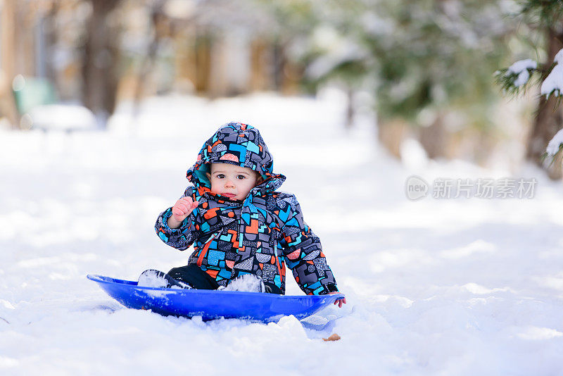 寒冷的小孩在雪地里玩雪橇
