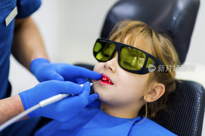 年轻女孩在牙科检查时戴着防护眼镜