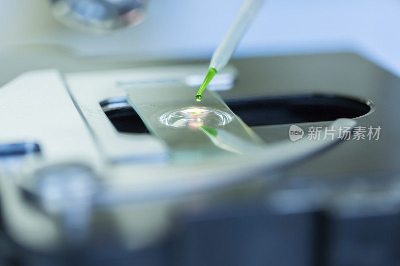 科学家在显微镜下将化学液体滴在载玻片上，概念科学与技术